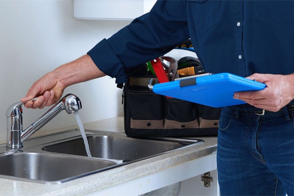 Technician Doling a Light Blue Clipboard and Adjust a Faucet Sink