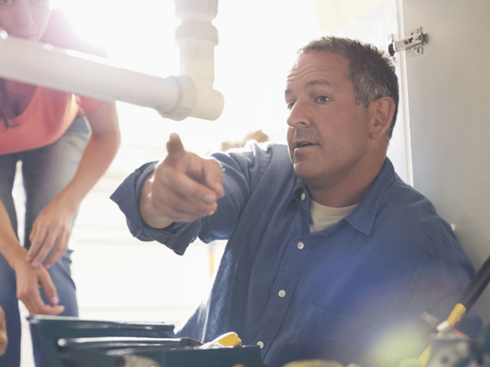 Plumber pointing out the plumbing problem to a customer