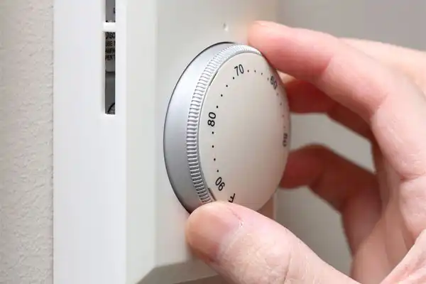 Hand adjusting temperature on thermostat