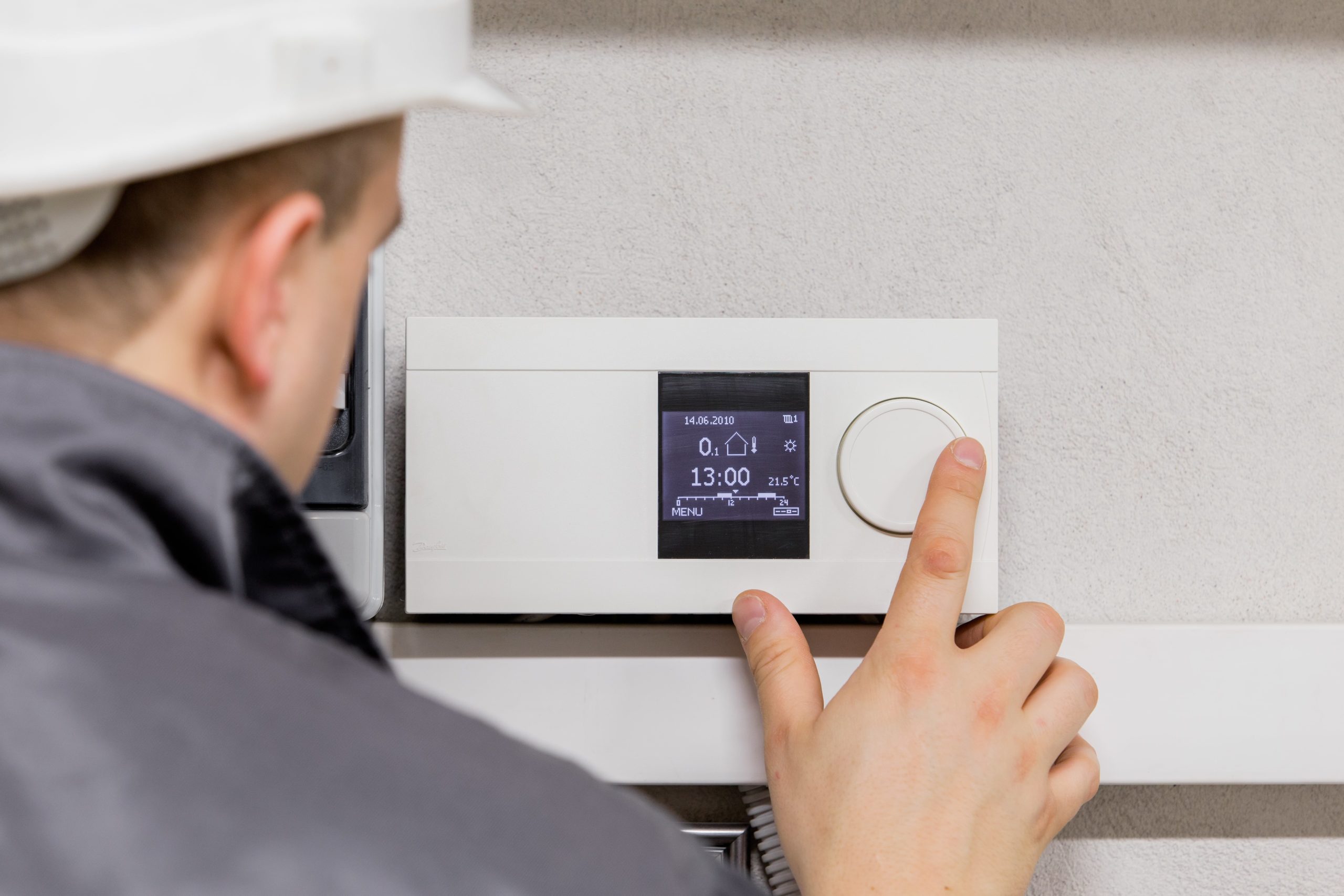 Technician Adjusting a Home Thermostat