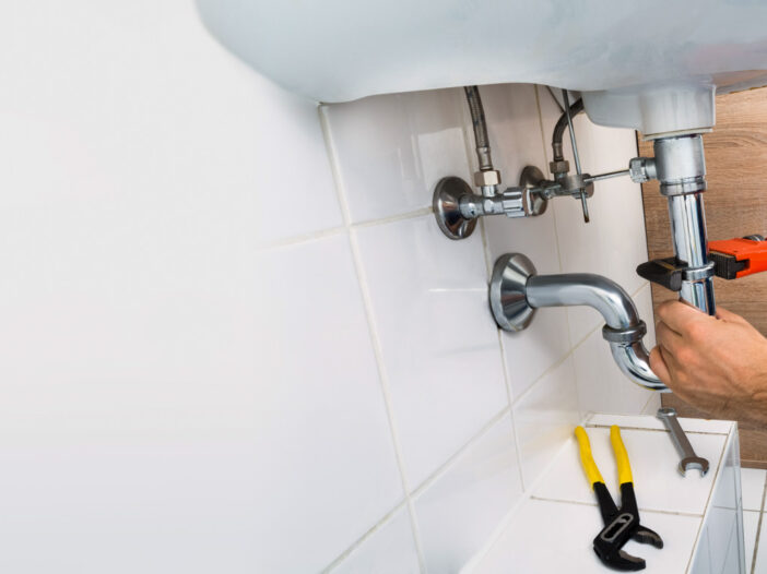 Plumbing Technician Fixing Sink Pipe with a Wrench